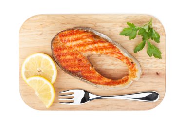 limon dilimleri ve maydanoz kesme tahtası üzerinde ızgara somon