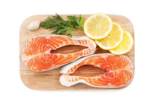 Salmon steaks with herbs and lemon slices on cutting board — Stock Photo, Image