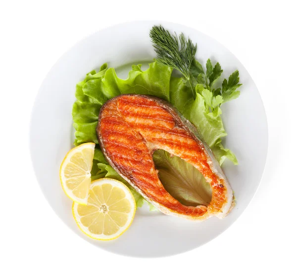 Grilled salmon with lemon slices and herbs on plate — Stock Photo, Image