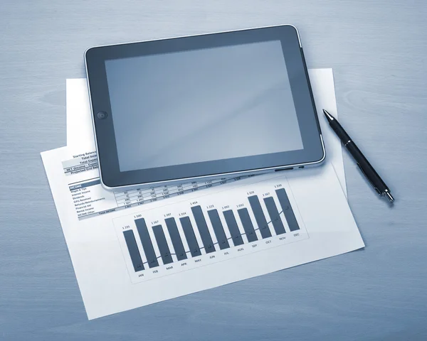 Tablet with blank screen over papers with numbers and charts — Stock Photo, Image