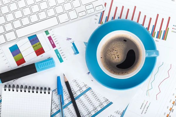 Blue coffee cup on financial papers — Stock Photo, Image