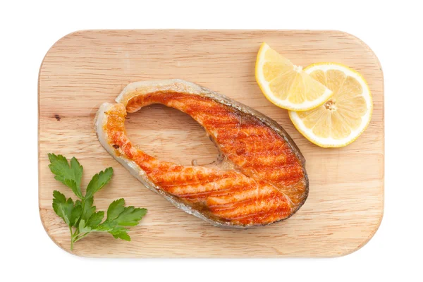 limon dilimleri ve maydanoz kesme tahtası üzerinde ızgara somon