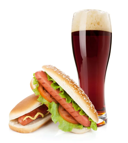 Donker bierglas en twee hotdogs met verschillende ingrediënten — Stockfoto