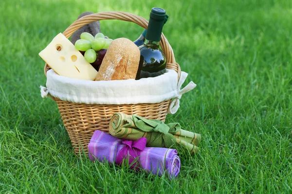 Cesta de piquenique ao ar livre com vinho no gramado — Fotografia de Stock