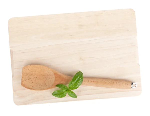 Cooking utensil and basil leaves over cutting board — Stock Photo, Image