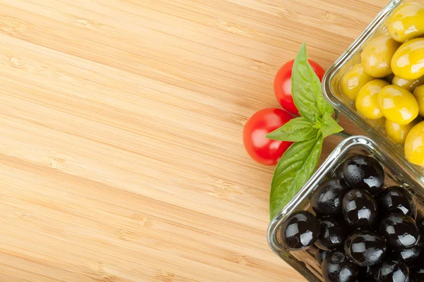 Olijven, tomaten en basilicum op snijplank — Stockfoto