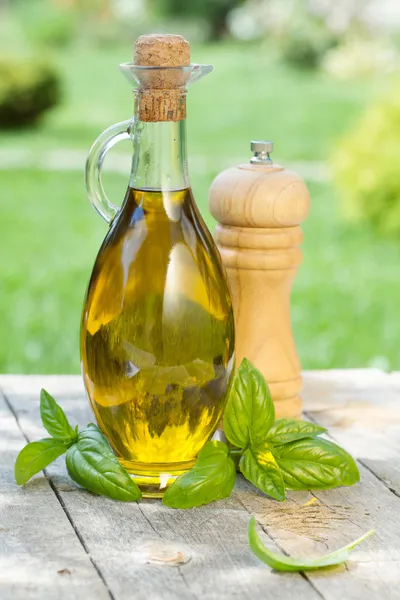 Бутылка оливкового масла, перцовый шейкер и базилик — стоковое фото