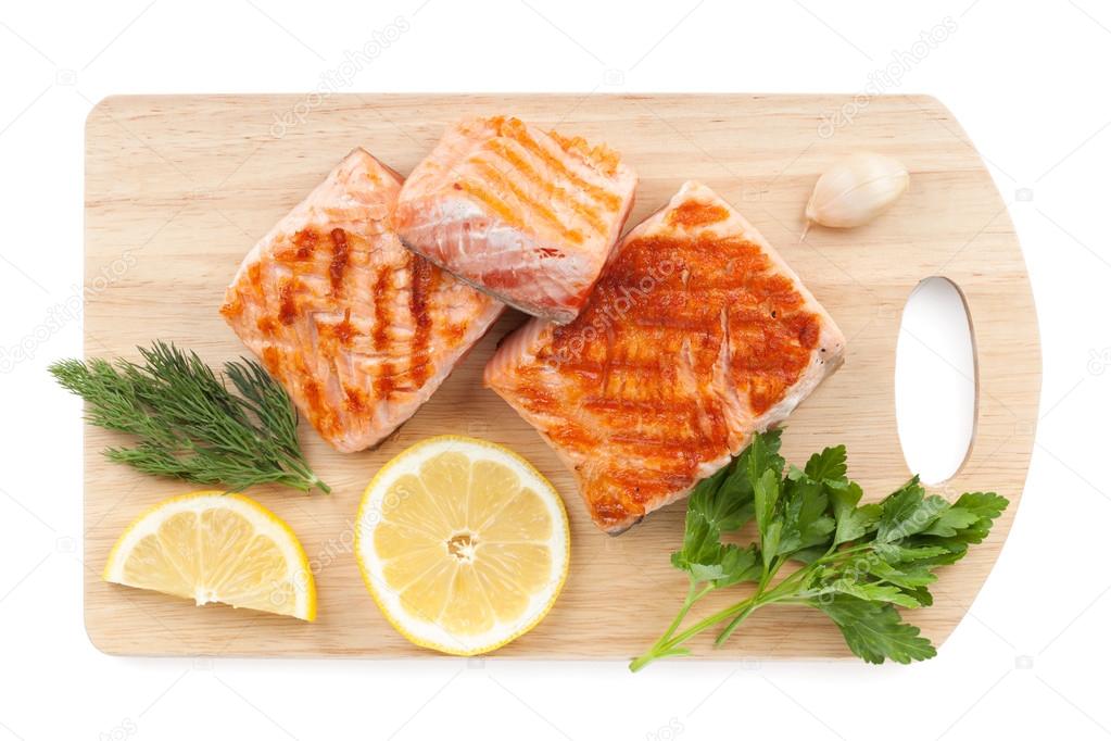 Grilled salmon with lemon slices and parsley on cutting board