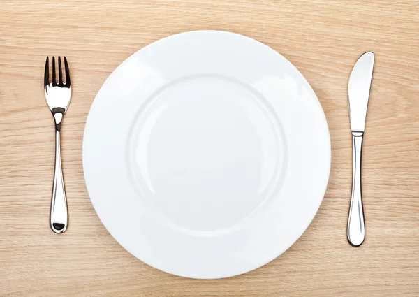 Empty white plate with silverware on wooden table — Stock Photo, Image