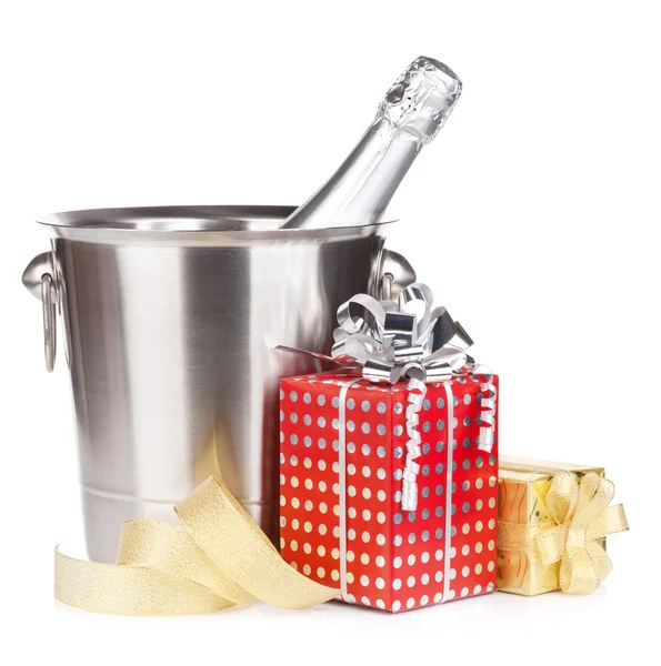 Champagne bottle in bucket and gift boxes — Stock Photo, Image