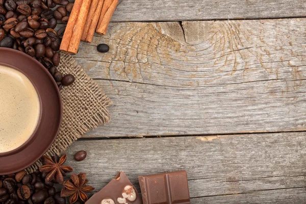 Šálek kávy s kořením a čokoládou na dřevěný stůl textury — Stock fotografie