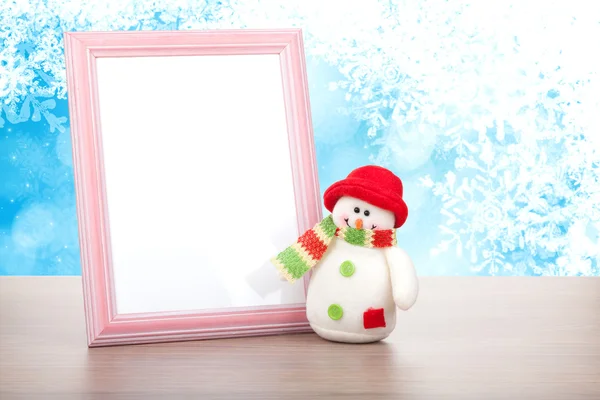 Moldura de foto em branco e boneco de neve de Natal na mesa de madeira — Fotografia de Stock