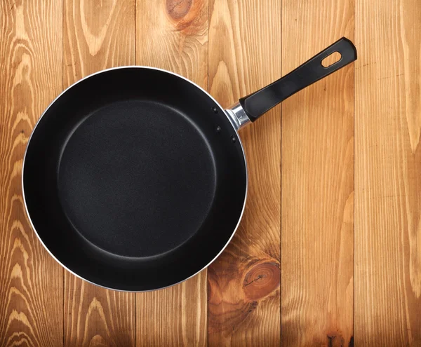 Frying pan on wooden table — Stock Photo, Image