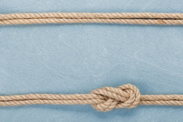 Ship rope knot on wooden texture background — Stock Photo, Image