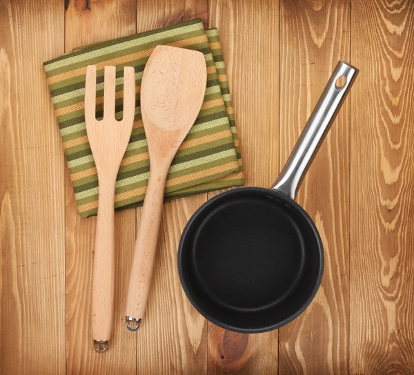 Frying pan and kitchen utensils on wooden table — Stock Photo, Image