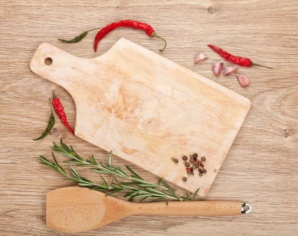 Skärbräda med kryddor runt över träbord — Stockfoto