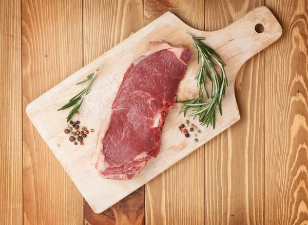 Raw sirloin steak with rosemary and spices on cutting board — Φωτογραφία Αρχείου