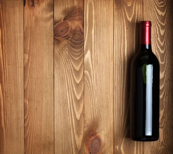 Ahşap masa arka plan üzerinde kırmızı şarap şişesi — Stok fotoğraf