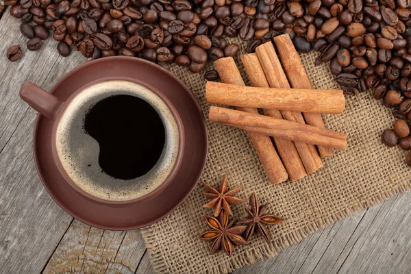 Šálek kávy a koření na dřevěný stůl — Stock fotografie