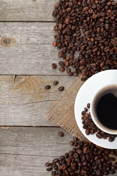 Kaffekopp och bönor på träbord — Stockfoto