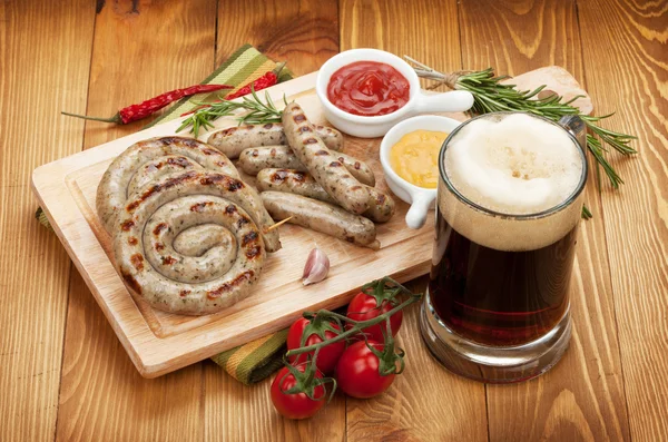 Grillwürste mit Ketchup, Senf und einem Becher Bier — Stockfoto