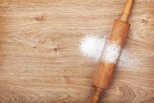 Ролик с мукой на деревянном столе
