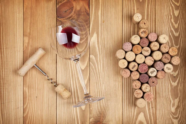 Copa de vino tinto, sacacorchos y corchos — Foto de Stock