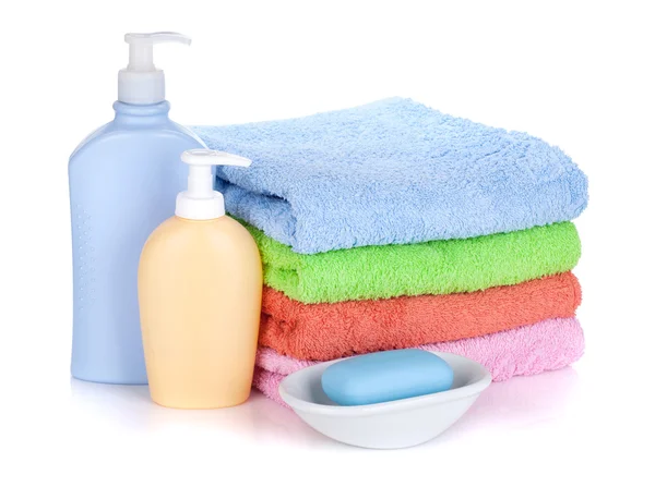 Cosmetics bottles, soap and colored towels — Stock Photo, Image