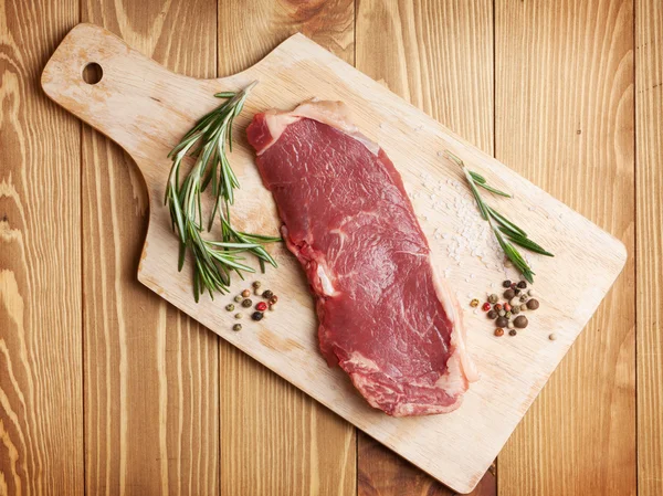 Biberiye ve baharat kesme tahtası üzerinde ham sığır filetosu biftek — Stok fotoğraf