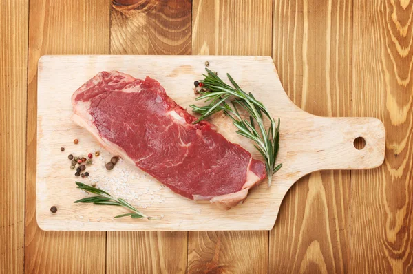 Ruwe entrecote met rozemarijn en specerijen op snijplank — Stockfoto