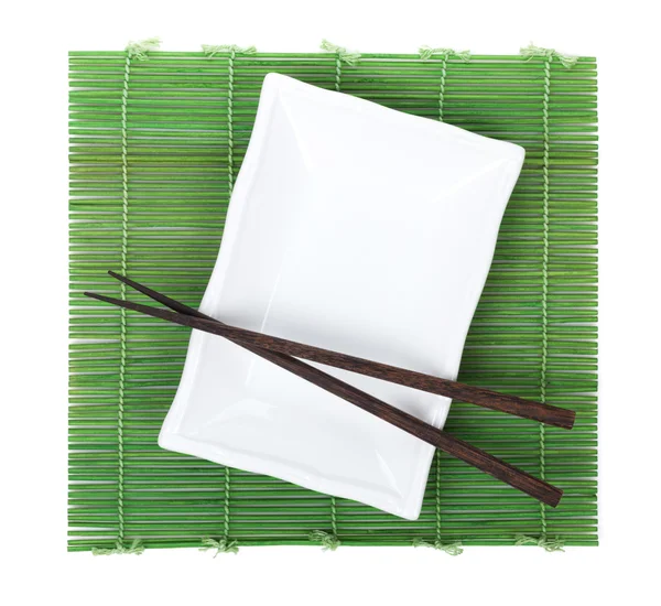 Essstäbchen und Teller über Bambusmatte — Stockfoto