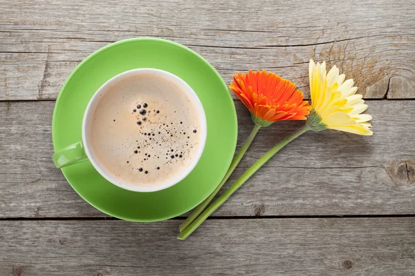 Taza de café y dos coloridas flores de gerbega — Foto de Stock