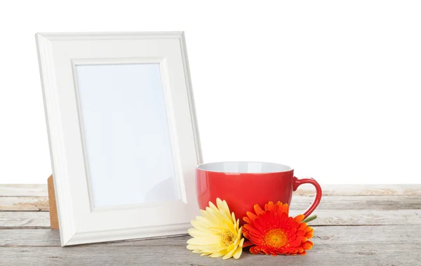 Photo frame with red cup and twocolorful gerbera flowers — Stock Photo, Image