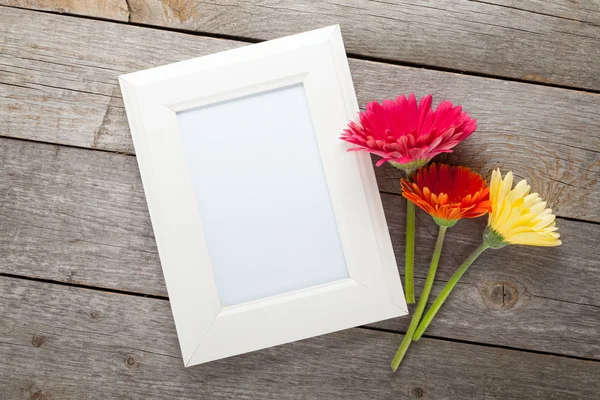 Three colorful gerbera flowers and photo frame — Stock Photo, Image