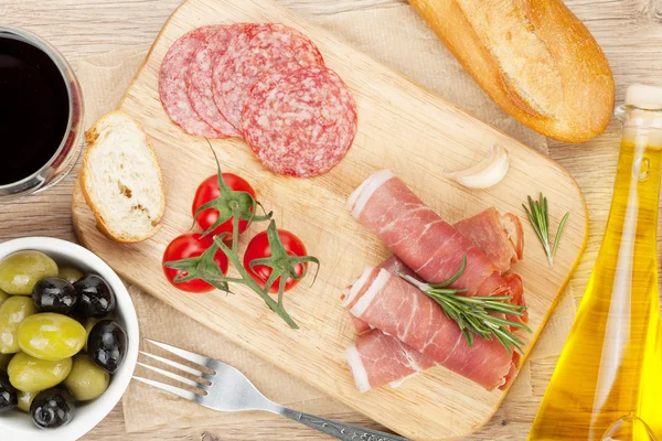 Red wine with cheese, prosciutto, bread, vegetables and spices — Stock Photo, Image