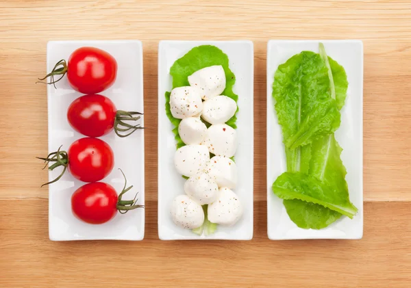 Tomates, mozzarella et feuilles de salade verte — Photo