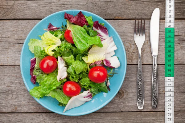 Verse gezonde salade, tomaten en keukengerei — Stockfoto