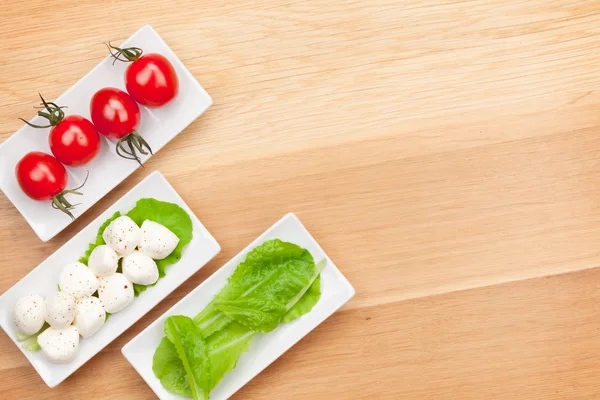 Tomatoes, mozzarella and green salad leaves — Stock Photo, Image