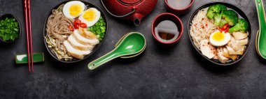 Tavuk, sebze, yumurta ve taştan arkaplanda bitki çayı ile Asya erişteli ramen çorbası. Üst görünüm düzlüğü