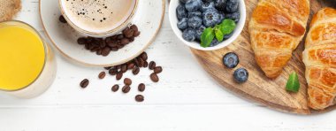 Kahve, kruvasan, portakal suyu ve böğürtlen kahvaltısı ahşap masada. Üst görünüm düzlüğü