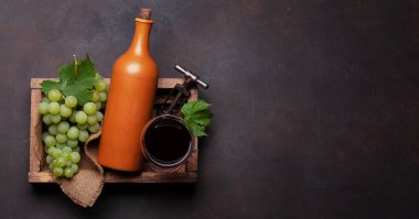 Kırmızı şarap kadehi, şişe ve tahta kutuda beyaz üzüm. Üst görünüm düzlüğü kopyalama alanı ile yatıyordu