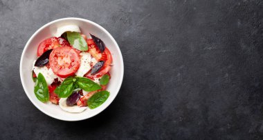Taze domatesli Caprese salatası, fesleğen ve mozzarella peyniri. Üst görünüm düzlüğü kopyalama alanı ile yatıyordu