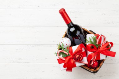 İçinde şampanya şişesi, dekor, hediye kutuları ve meyveler olan Noel hediyesi sepeti. Üst görünüm düzlüğü kopyalama alanı ile yatıyordu