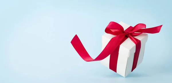 白色礼品盒 蓝色底色上有红丝带 给你的圣诞 生日或情人节的祝福留出空间 — 图库照片