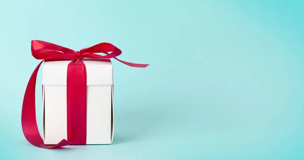 白色礼品盒 蓝色底色上有红丝带 给你的圣诞 生日或情人节的祝福留出空间 — 图库照片