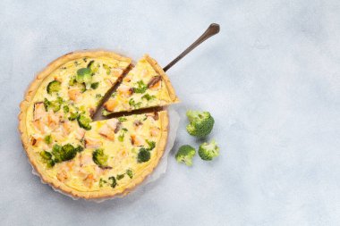 Ev yapımı balık turtası. Mutfak masasında açık yüzlü somon balığı ve brokoli turtası. Üst görünüm düzlüğü