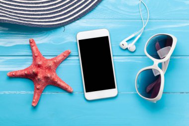 Seyahat ve tatil konsepti. Aksesuarlar ve eşyalar. Güneş şapkası, güneş gözlüğü, akıllı telefon ve deniz yıldızı. Üst görünüm düzlüğü kopyalama alanı ile yatıyordu