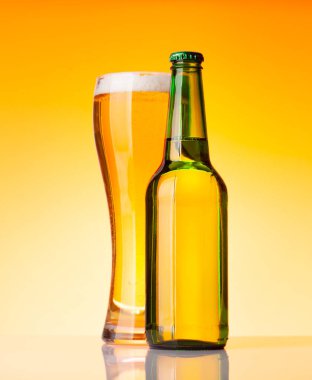 Bira şişesi ve bira, sarı arka planda bira. Stüdyo çekimi