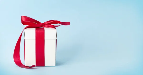 Λευκό Κουτί Δώρου Κόκκινη Κορδέλα Πάνω Από Μπλε Φόντο Χώρο — Φωτογραφία Αρχείου