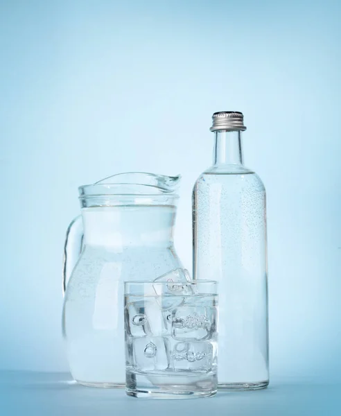 Vattenflaska Kanna Och Glas Med Vatten Och Isbitar Över Blå — Stockfoto